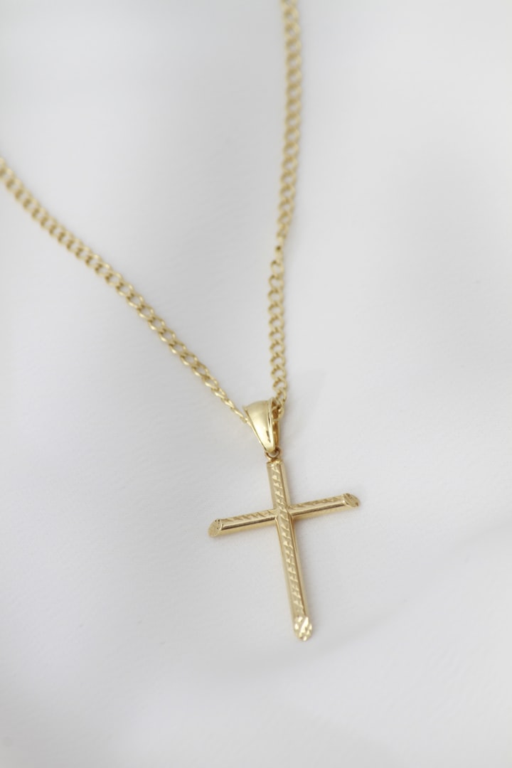 A gold cross necklace on a white mannequin